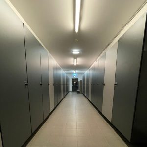 Langer Korridor mit vielen grauen Türen und Deckenleuchten | Toptrock